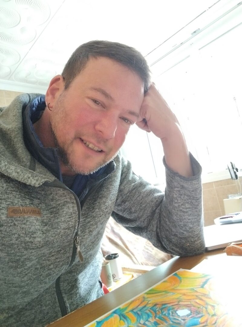 Trevett Allen at a drawing table, looking up from a work in progress.