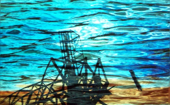 A dark industrial structure stands against turquoise ripples.